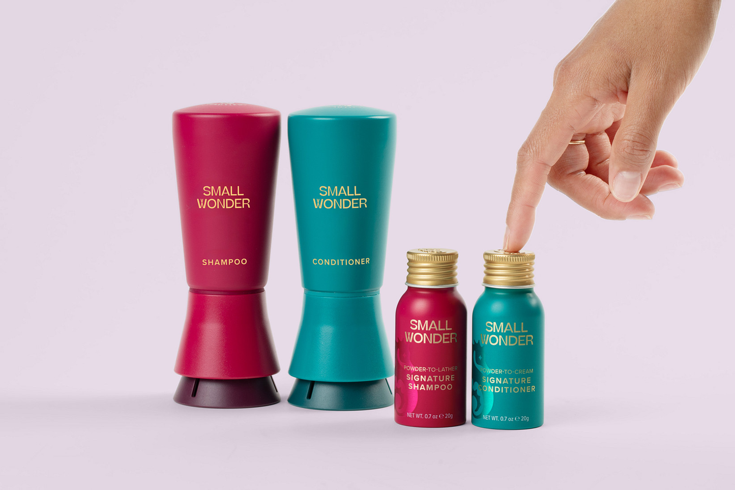 Small Wonder shampoo and conditioner bottles with a hand pointing to them on a light purple background