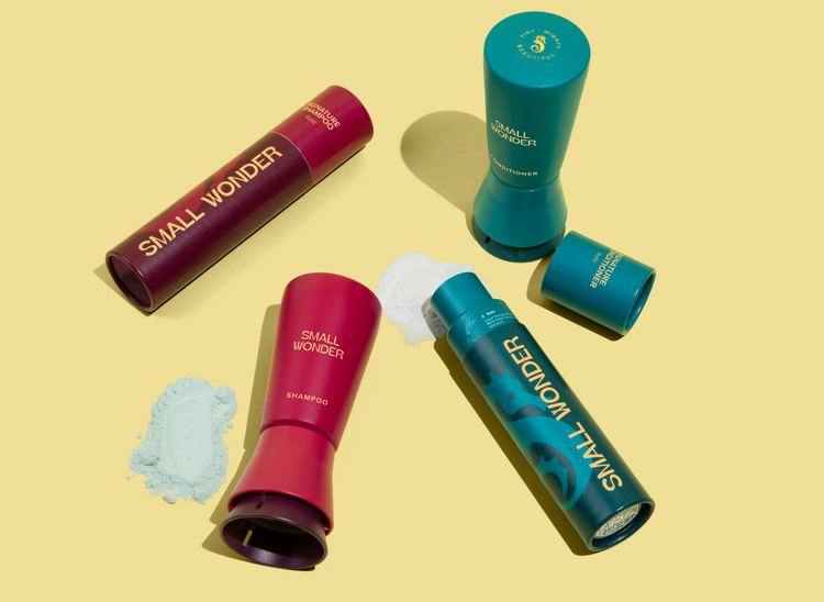Small Wonder red Shampoo and teal Conditioner bottles and refill tubes with piles of green powder